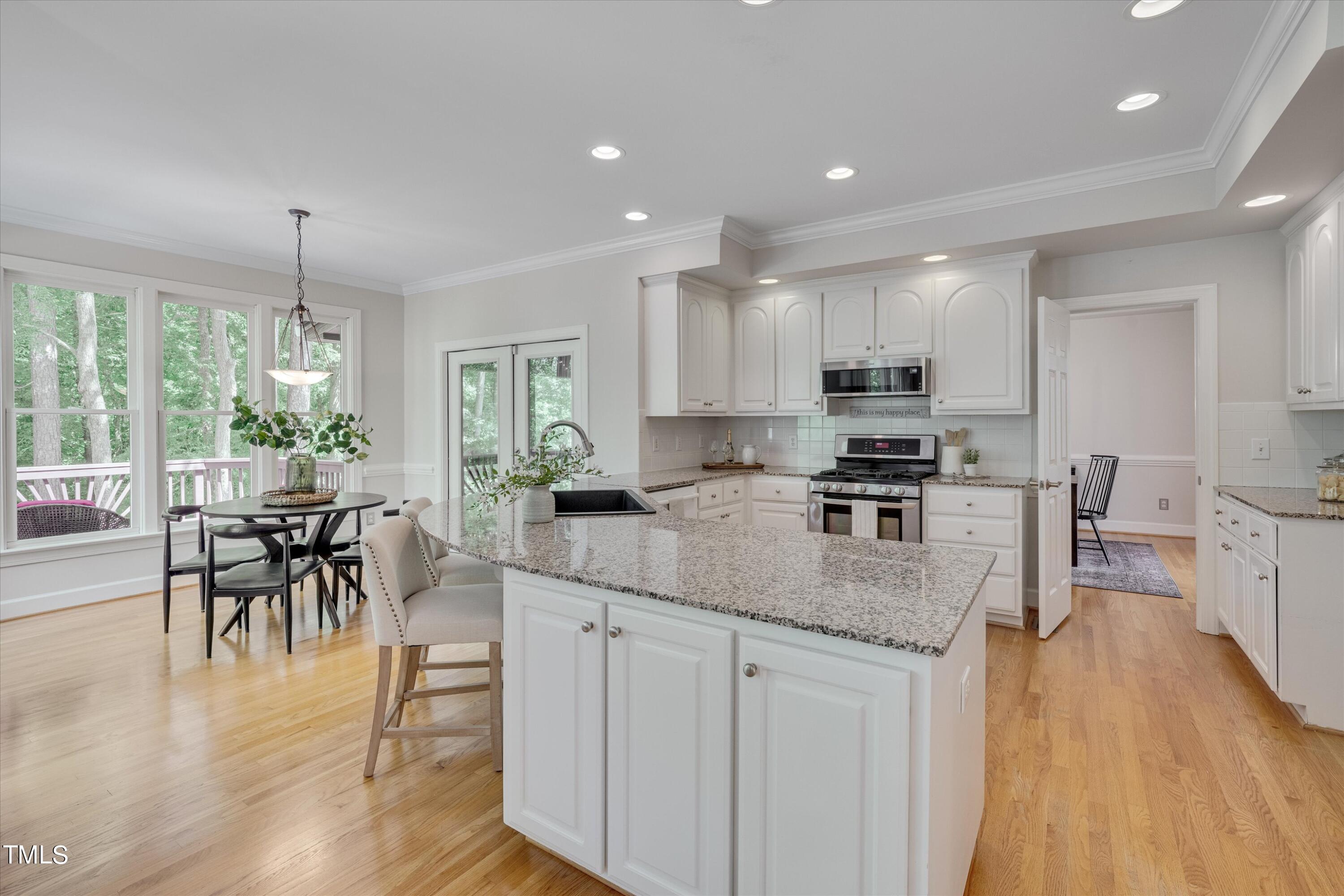 116 Ashworth Drive Durham, NC 27707 - Photo 17 of 60 a kitchen with stainless steel appliances granite countertop a stove top oven a sink a dining table and chairs with wooden floor