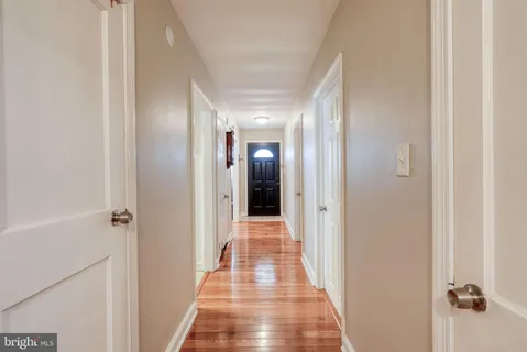 a view of a hallway with wooden floor and a bathroom