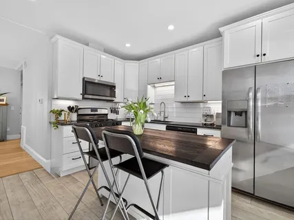 a kitchen with kitchen island a refrigerator a stove a sink and white cabinets
