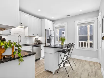 a kitchen with stainless steel appliances granite countertop a table chairs in it and wooden floors
