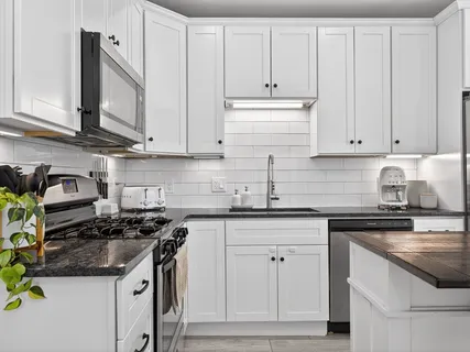 a kitchen with granite countertop white cabinets and white appliances