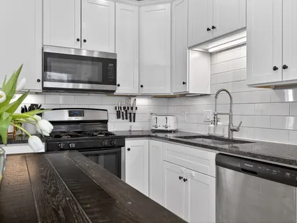a kitchen with stainless steel appliances granite countertop a sink a stove a microwave and cabinets