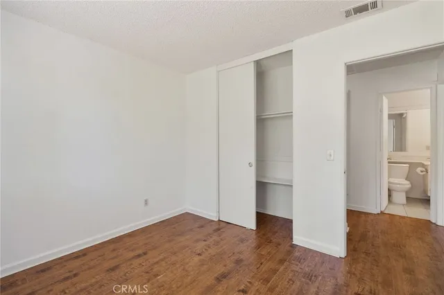 a view of empty room with wooden floor and bathroom