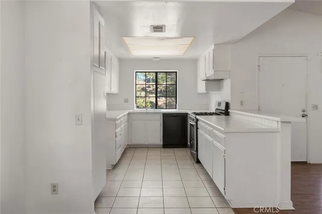 a kitchen with a sink a stove cabinets and a window
