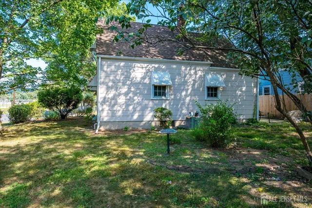 a backyard of a house with plants and large tree