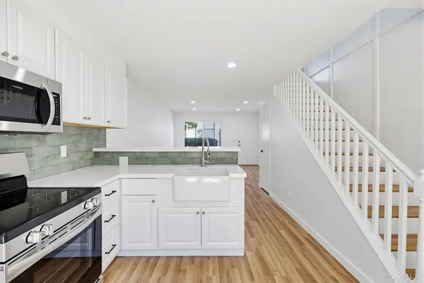 a kitchen with white cabinets appliances and a sink