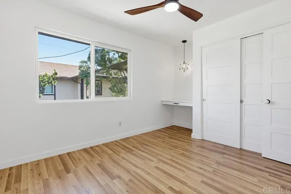 an empty room with wooden floor cabinet and windows