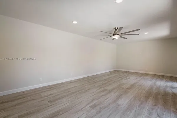 a view of a room with wooden floor and a ceiling fan