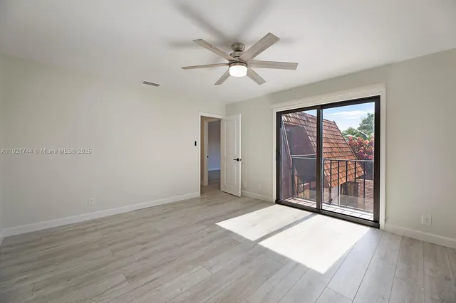 an empty room with wooden floor fan and windows