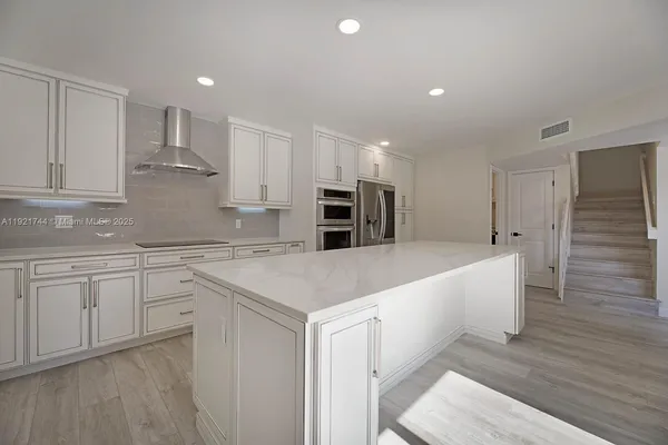 a large kitchen with stainless steel appliances granite countertop a white stove top oven and white cabinets