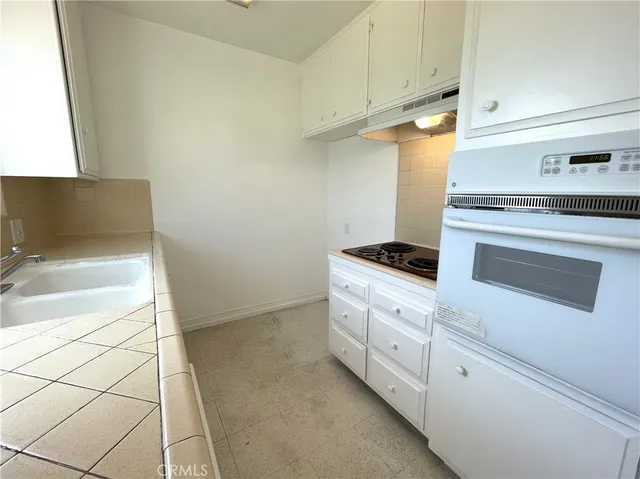 a kitchen with granite countertop white cabinets and white appliances