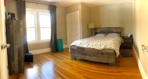 a bedroom with a bed and wooden floor