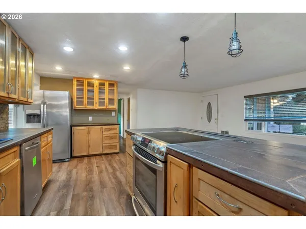 a kitchen with stainless steel appliances granite countertop a sink a stove and a wooden floors