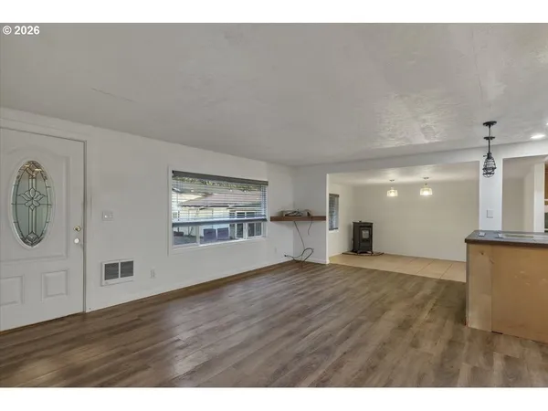 a view of an empty room with window and wooden floor
