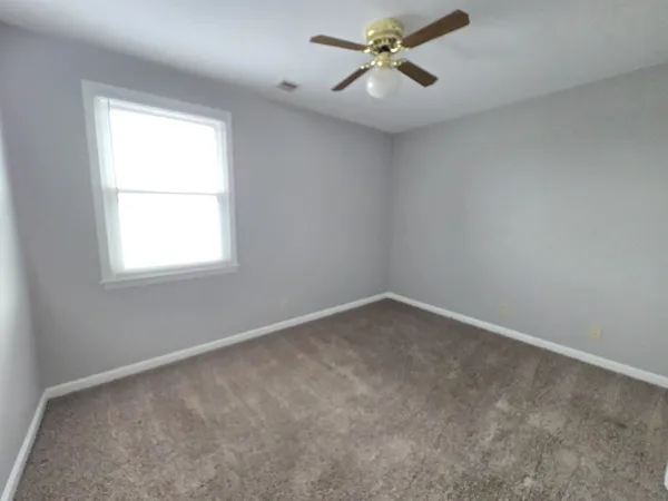 an empty room with a window and a fan