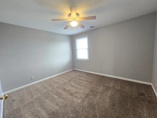 an empty room with windows and ceiling fan
