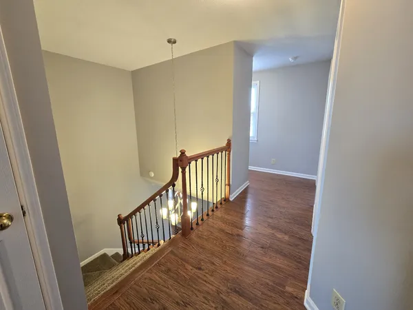 a view of a hallway with wooden floor and staircase