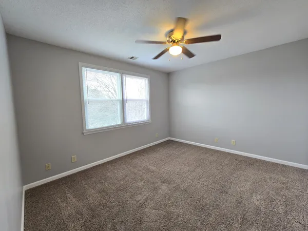 an empty room with a window and a fan