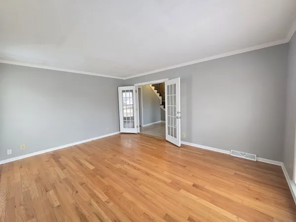 a view of an empty room with wooden floor and windows