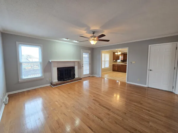 an empty room with wooden floor fireplace and windows