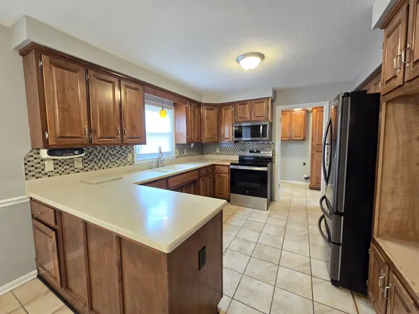 a kitchen with stainless steel appliances a stove a sink dishwasher a refrigerator and a microwave