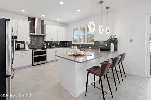 a kitchen with stainless steel appliances granite countertop a stove top oven a sink a dining table and chairs with wooden floor