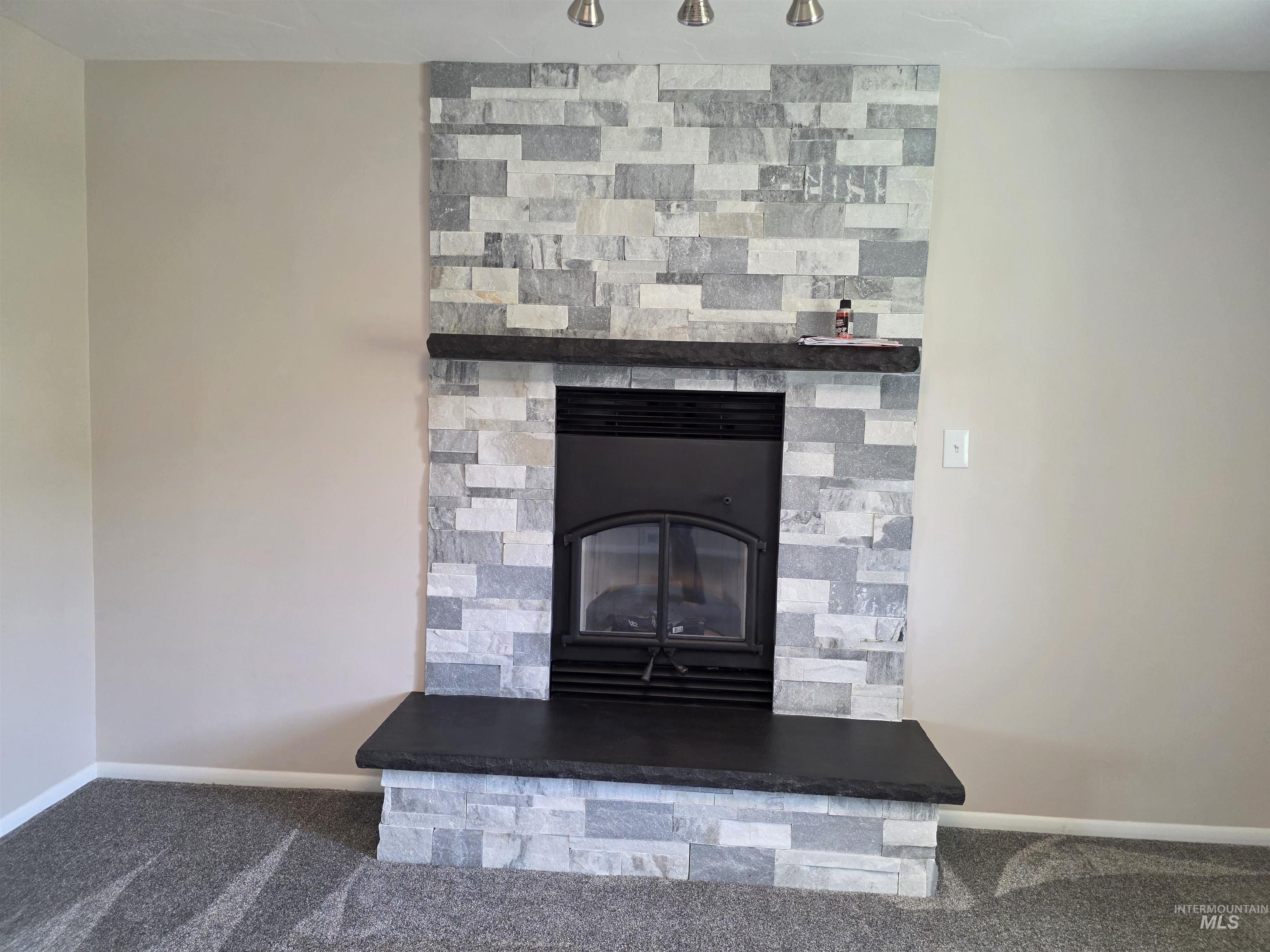 107 Pine Road Kamiah, ID 83536 - Photo 15 of 41 Stone-accented fireplace featuring a black insert, a deep hearth, and an integrated mantle shelf