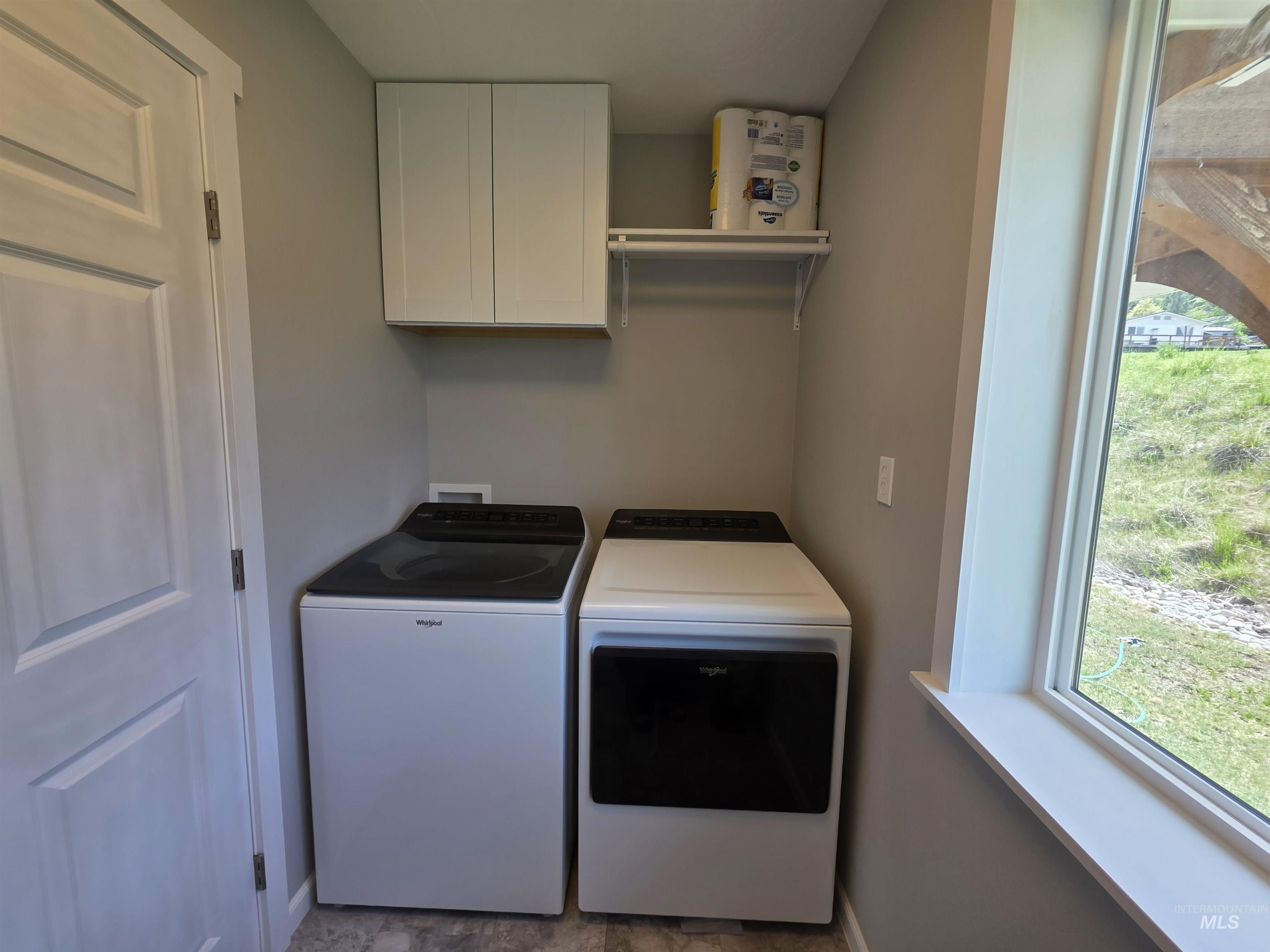 107 Pine Road Kamiah, ID 83536 - Photo 18 of 41 Laundry area featuring light gray wall paint, a window with white trim, and white shaker-style upper cabinetry