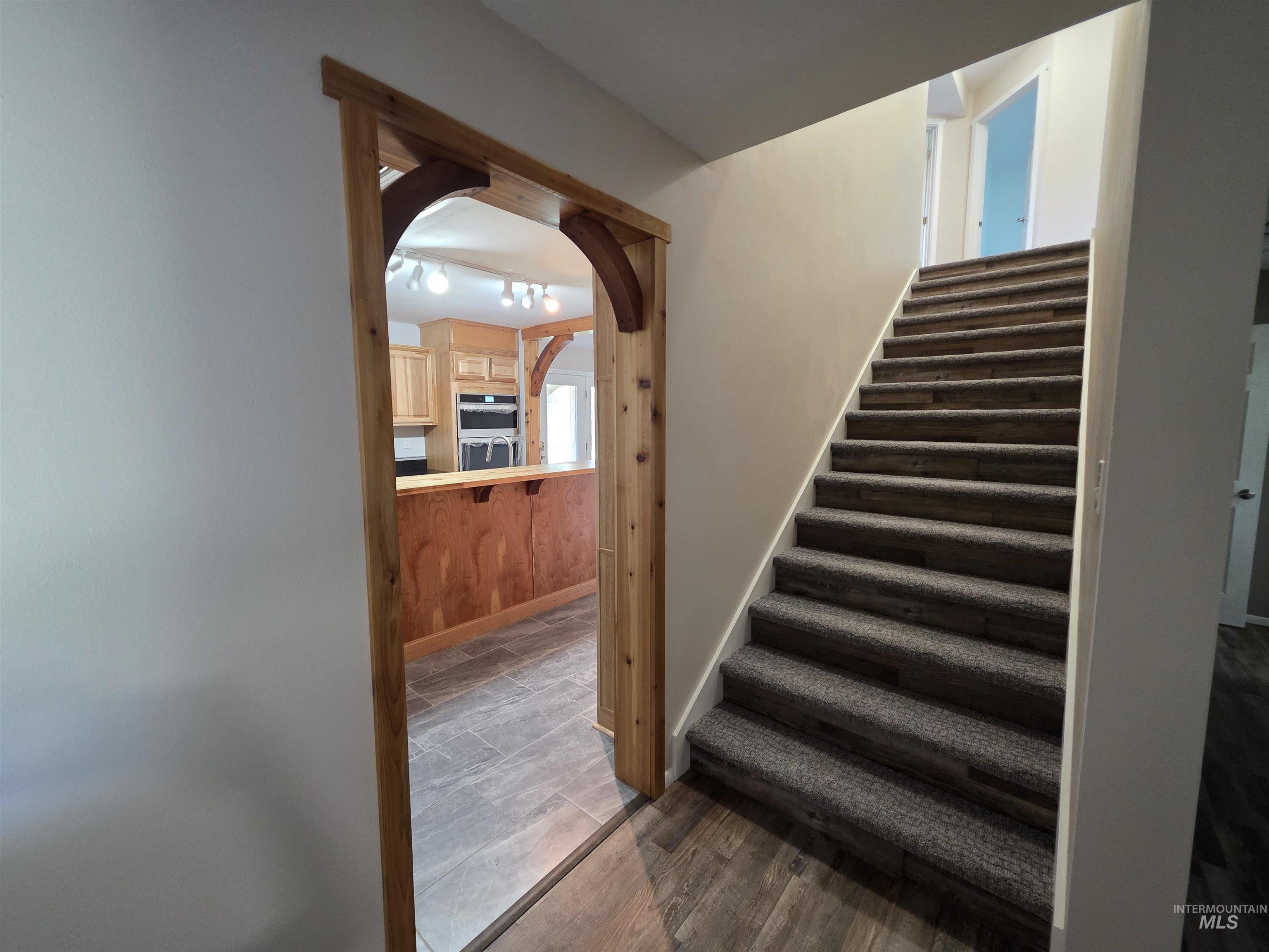 107 Pine Road Kamiah, ID 83536 - Photo 21 of 41 Carpeted staircase with wood-finish risers, wood-finish flooring, and a wood-trimmed archway