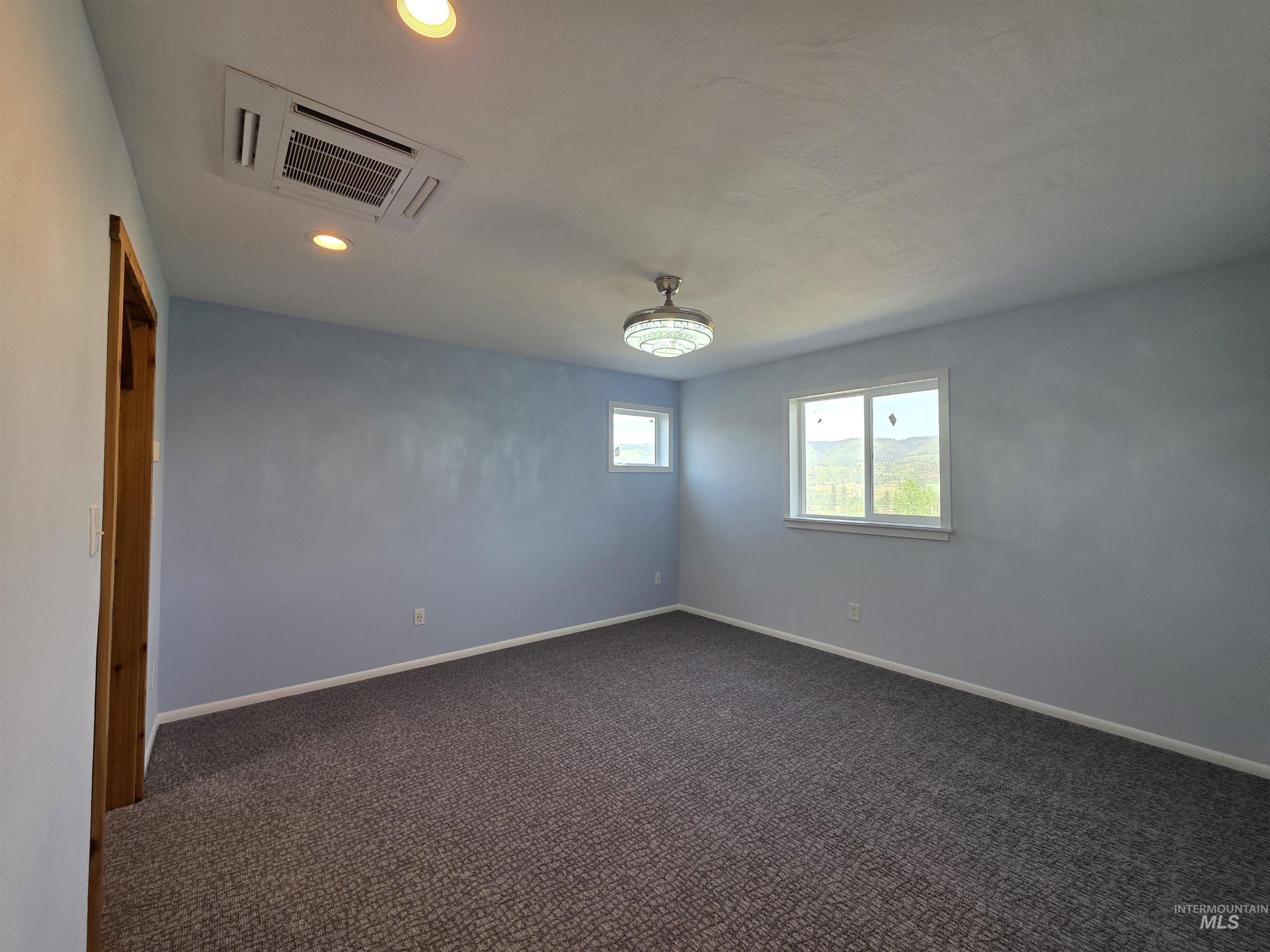107 Pine Road Kamiah, ID 83536 - Photo 22 of 41 Spacious room featuring light blue walls, patterned carpet flooring, and two windows offering natural scenery