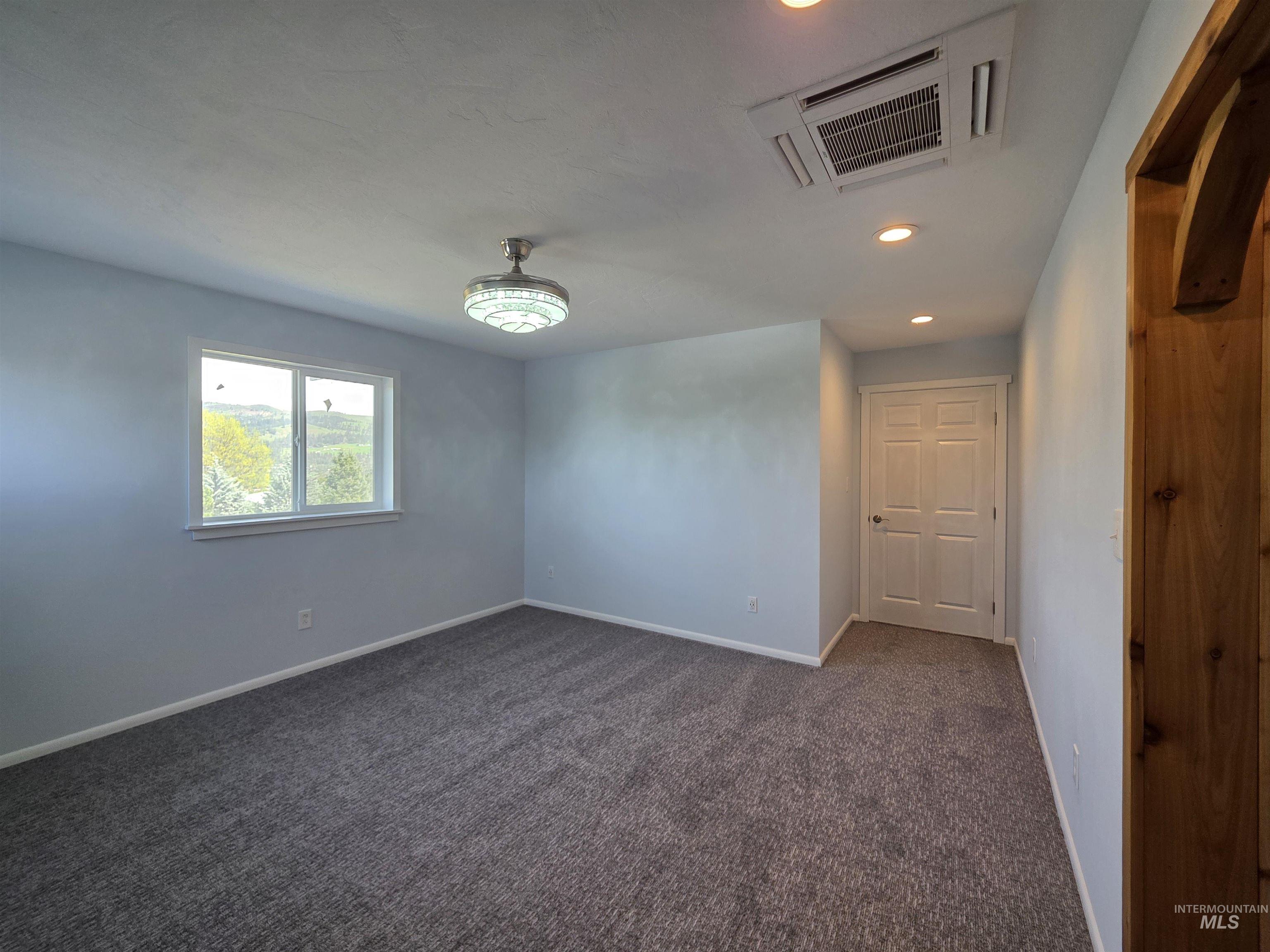107 Pine Road Kamiah, ID 83536 - Photo 23 of 41 Spacious room featuring plush gray carpeting, a large window, recessed lighting, and a decorative ceiling light fixture
