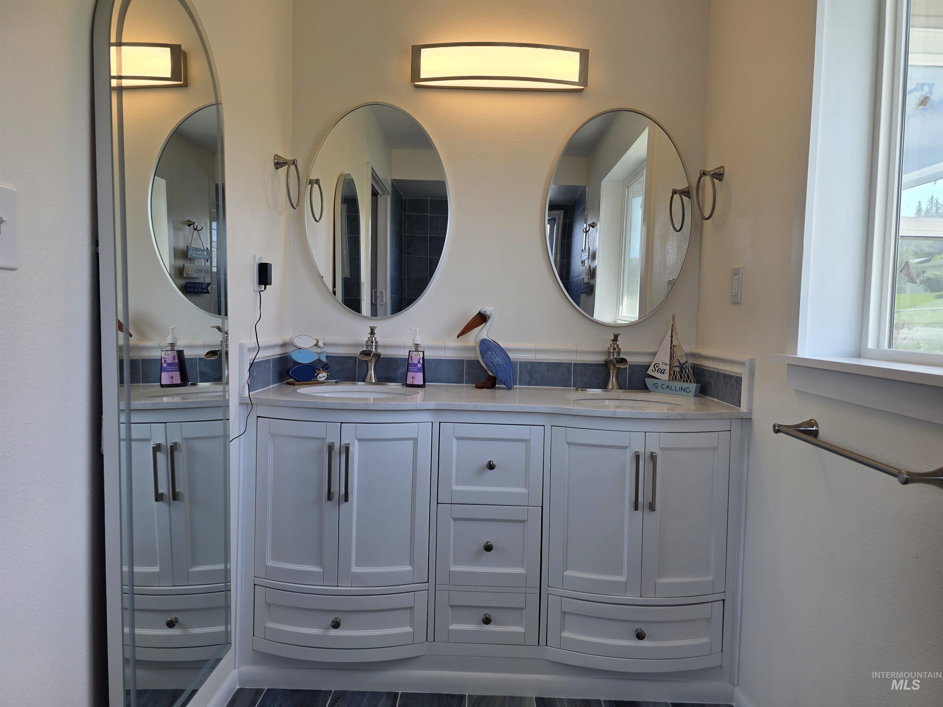 107 Pine Road Kamiah, ID 83536 - Photo 26 of 41 Double vanity featuring dual oval mirrors, two undermount sinks, and a light-toned countertop