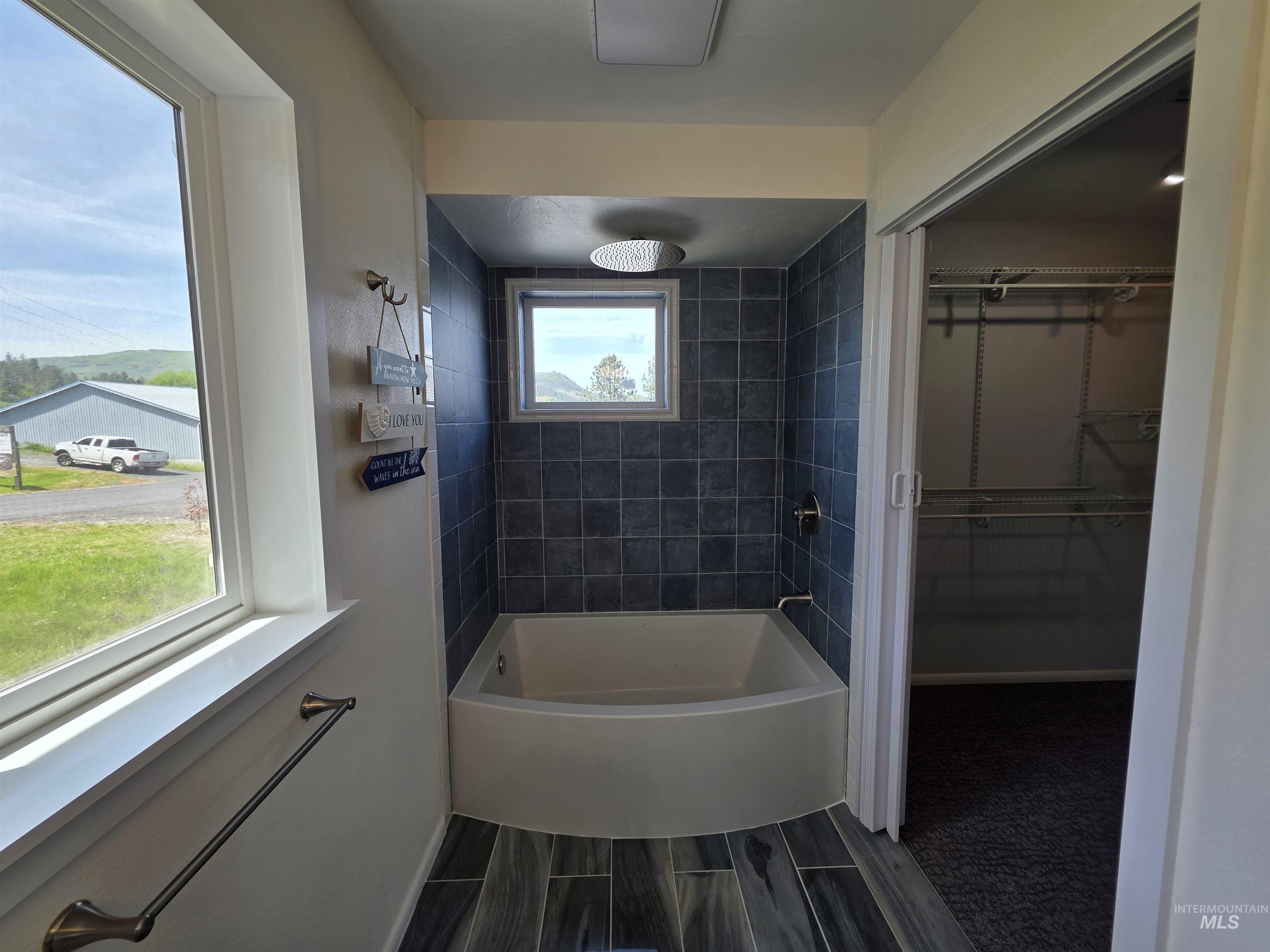 107 Pine Road Kamiah, ID 83536 - Photo 28 of 41 Bathroom featuring a built-in tub with dark square tile surround, rain shower head, and an adjacent window