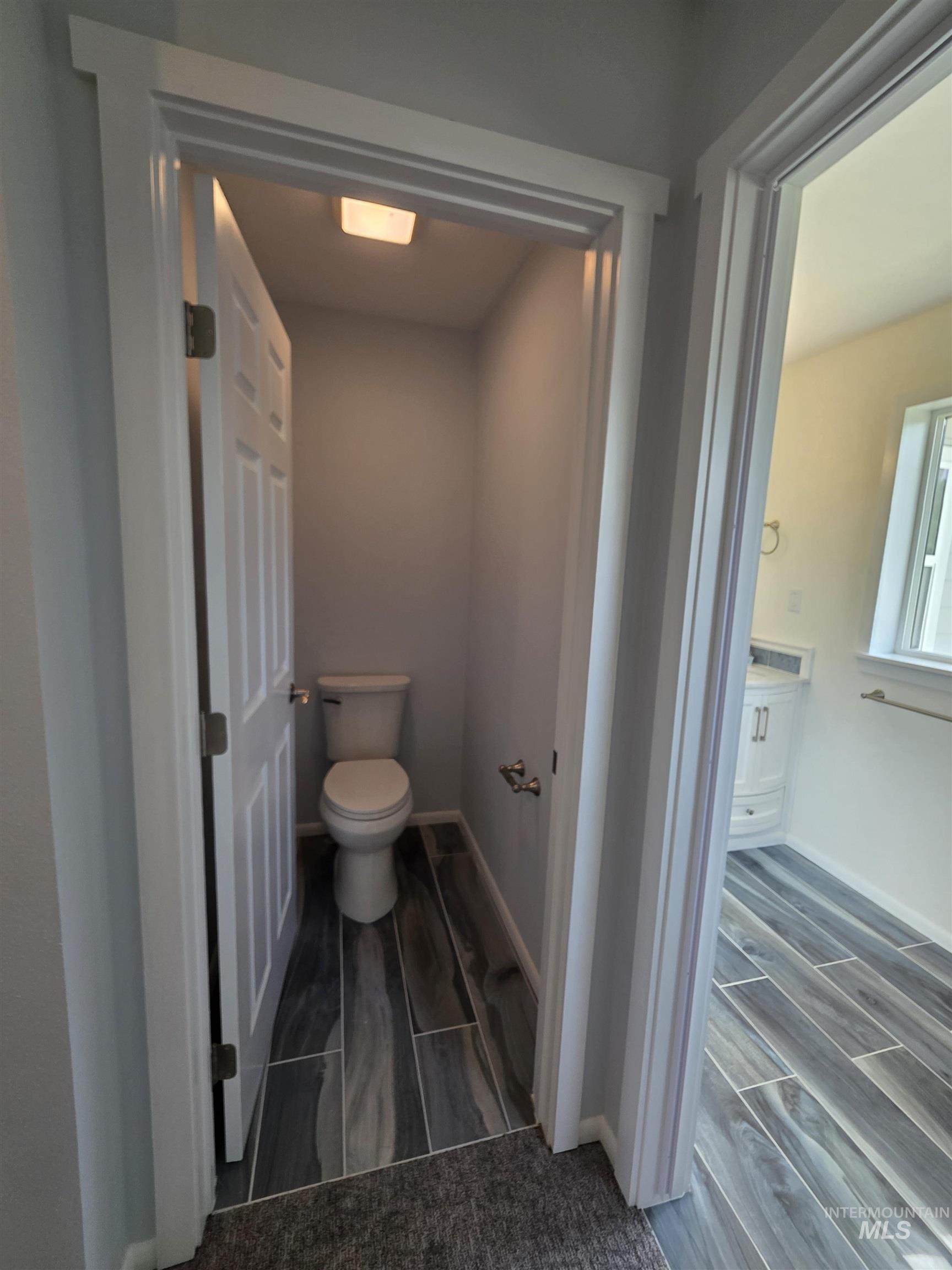 107 Pine Road Kamiah, ID 83536 - Photo 29 of 41 Private toilet room with wood-finish tile flooring, a white toilet, and a flush-mount ceiling light