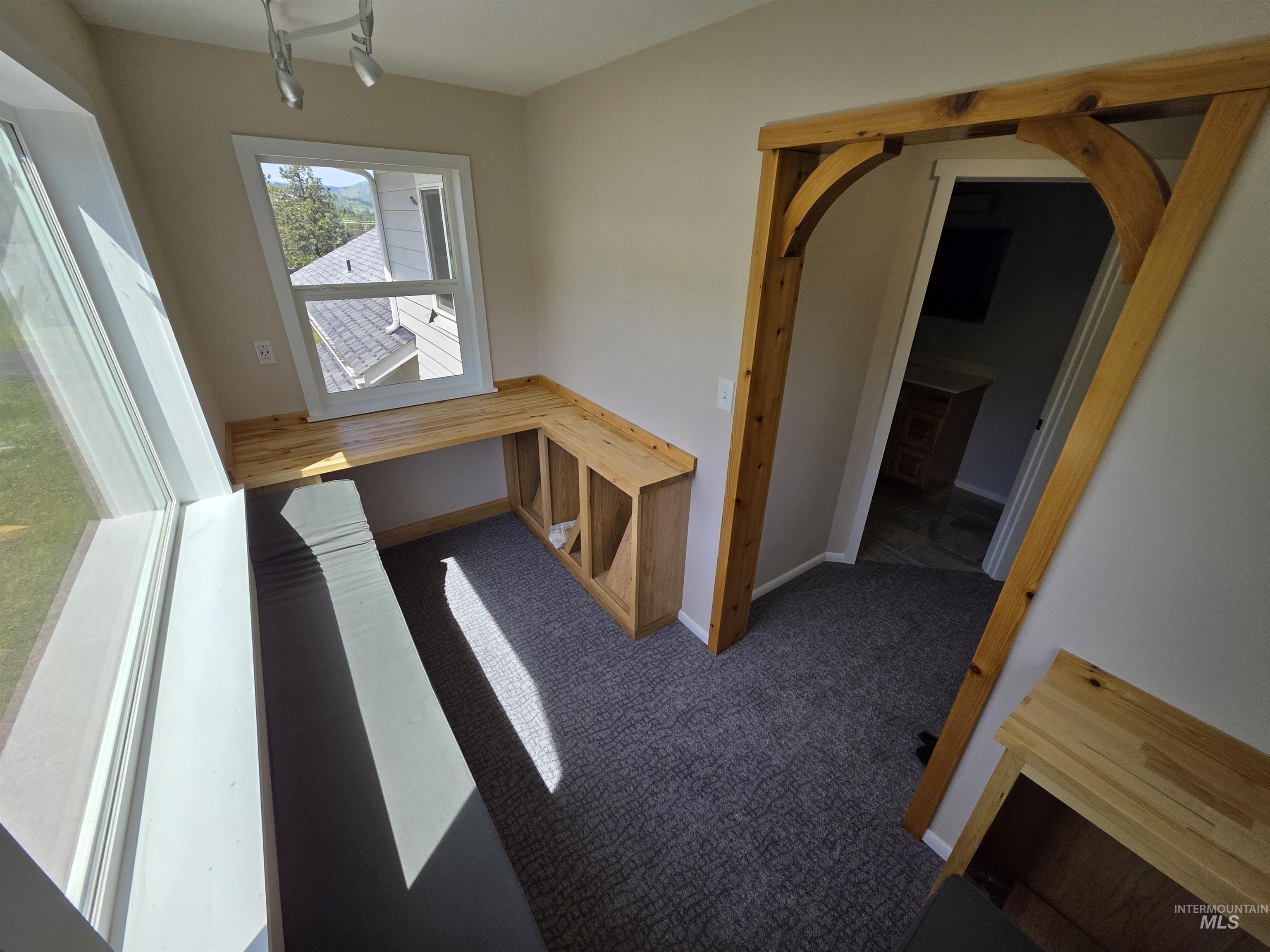 107 Pine Road Kamiah, ID 83536 - Photo 31 of 41 Room featuring a built-in wood-finish desk with open shelving, an arched wood-beam doorway, and track lighting