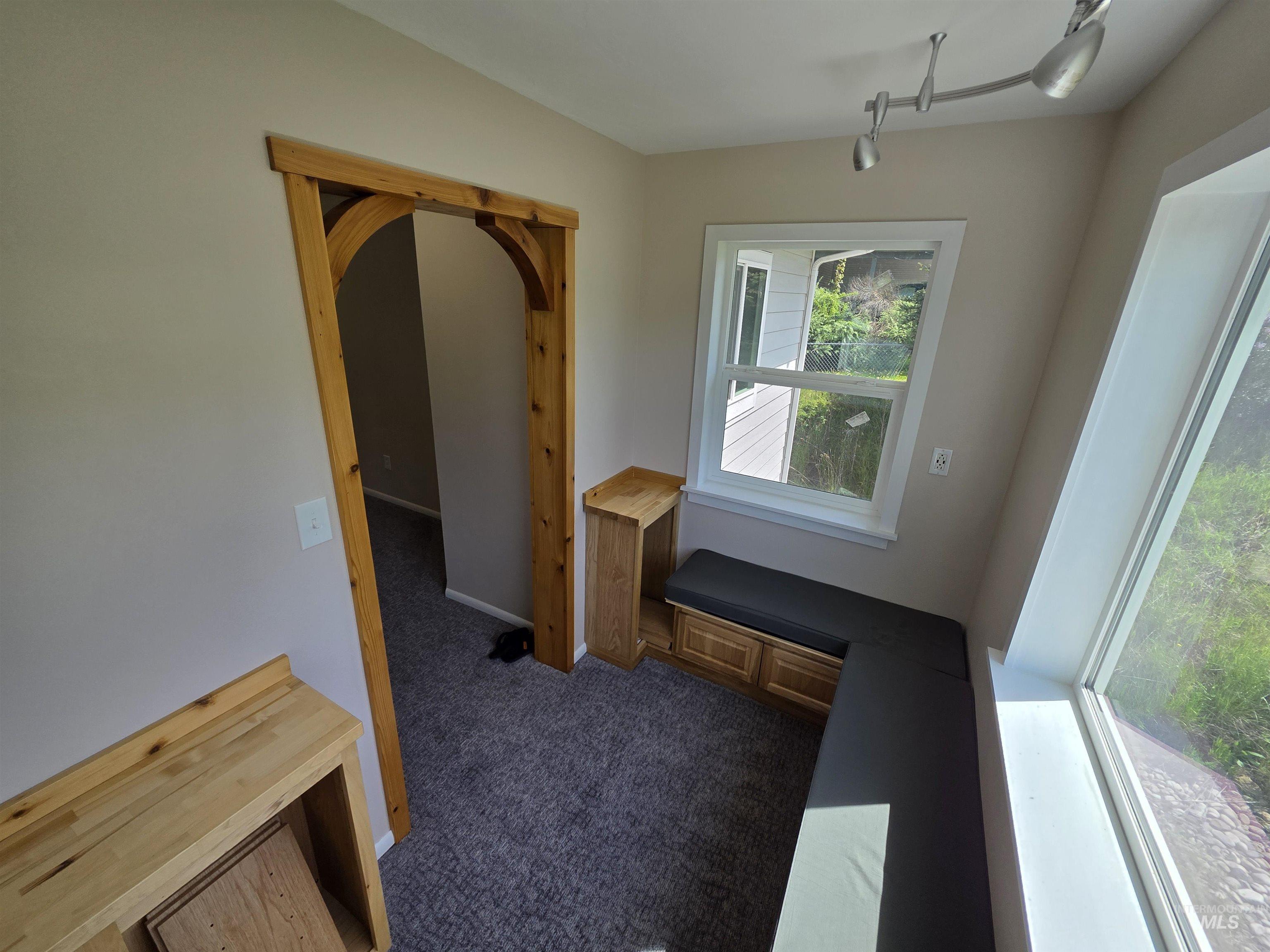 107 Pine Road Kamiah, ID 83536 - Photo 32 of 41 Built-in window seating with cushion, dual-pane windows, wood-finish arched doorway, track lighting, and soft gray carpeting