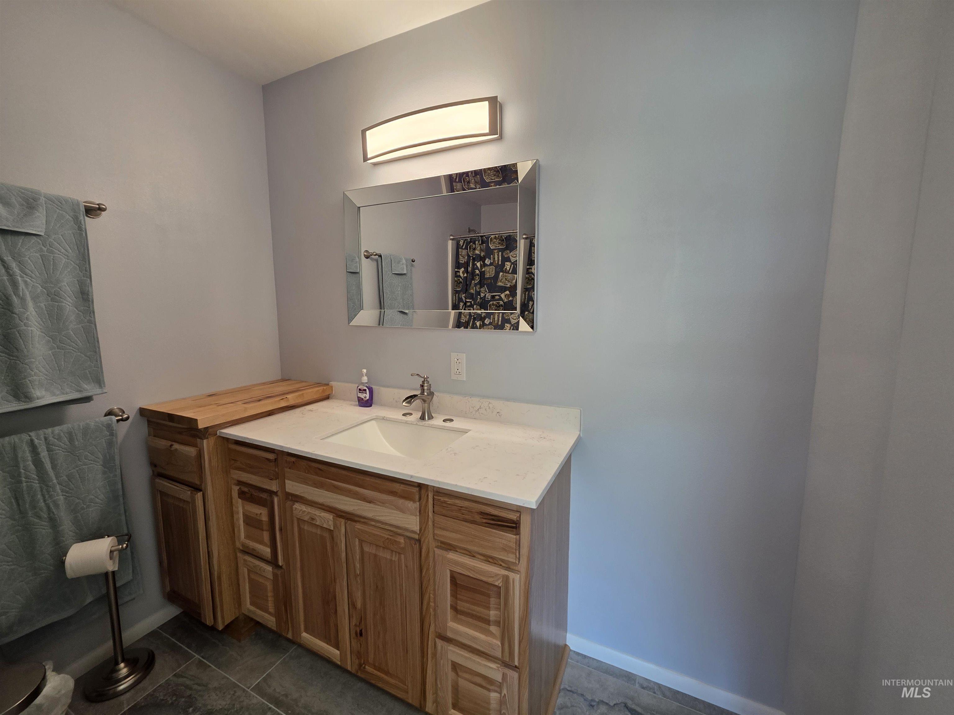 107 Pine Road Kamiah, ID 83536 - Photo 35 of 41 Bathroom vanity featuring natural wood cabinetry, a white countertop with an integrated sink, and a brushed nickel faucet