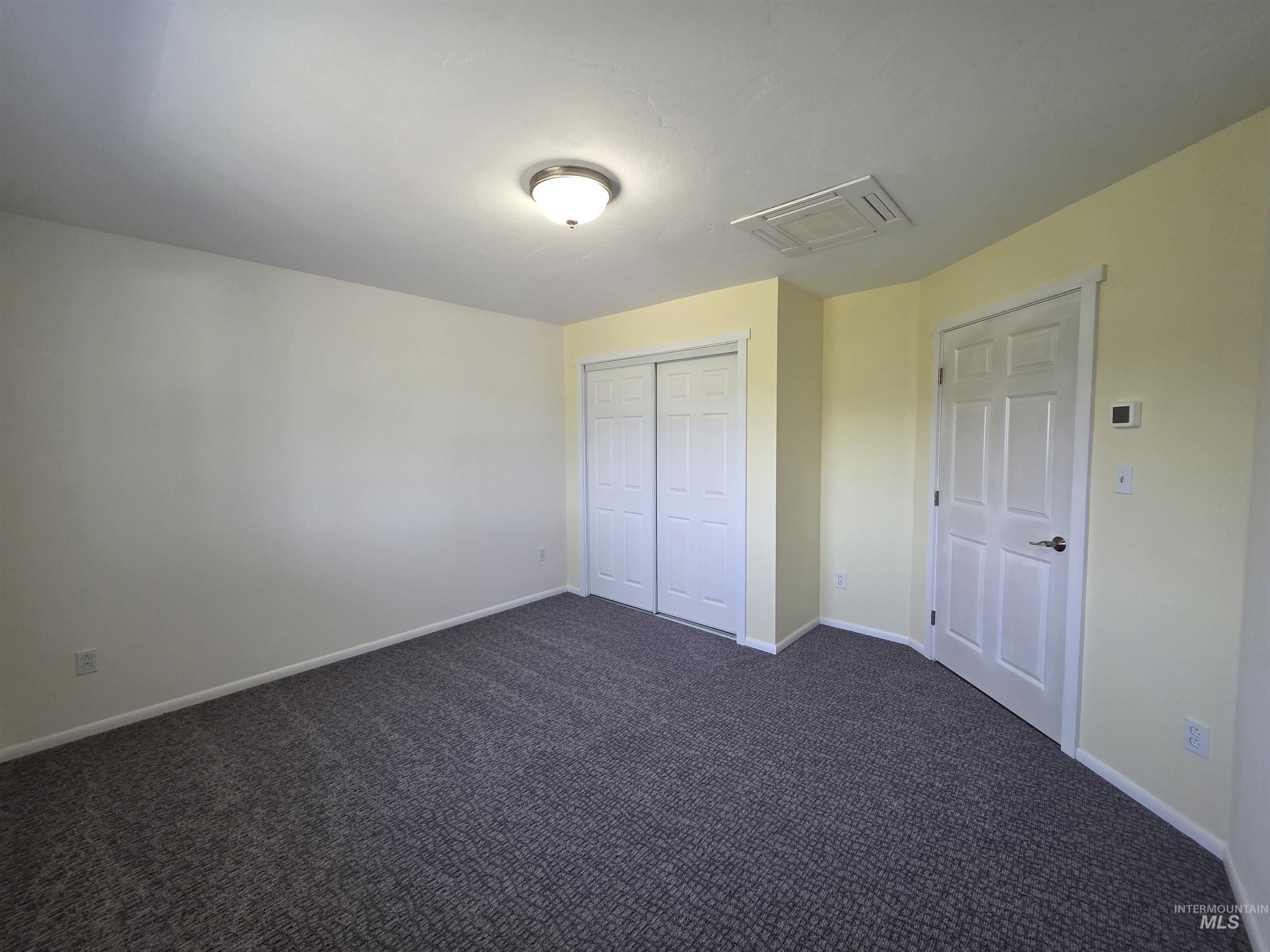 107 Pine Road Kamiah, ID 83536 - Photo 38 of 41 Carpeted room featuring a ceiling-mounted light fixture, sliding closet doors, a panel door, and an integrated ceiling ventilation unit