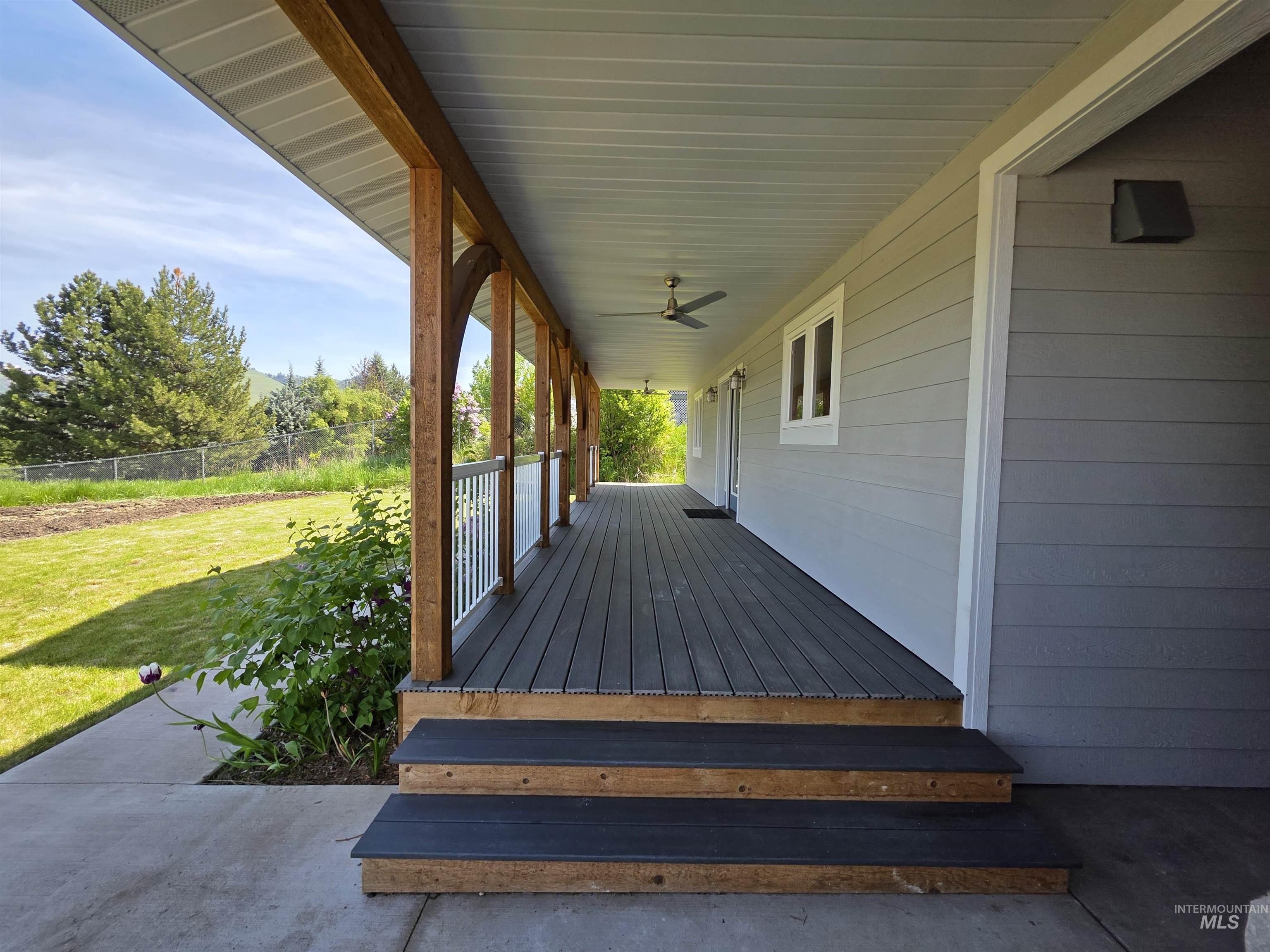 107 Pine Road Kamiah, ID 83536 - Photo 6 of 41 Expansive covered porch featuring wood-finish support beams, a dark-toned composite deck, and white railing