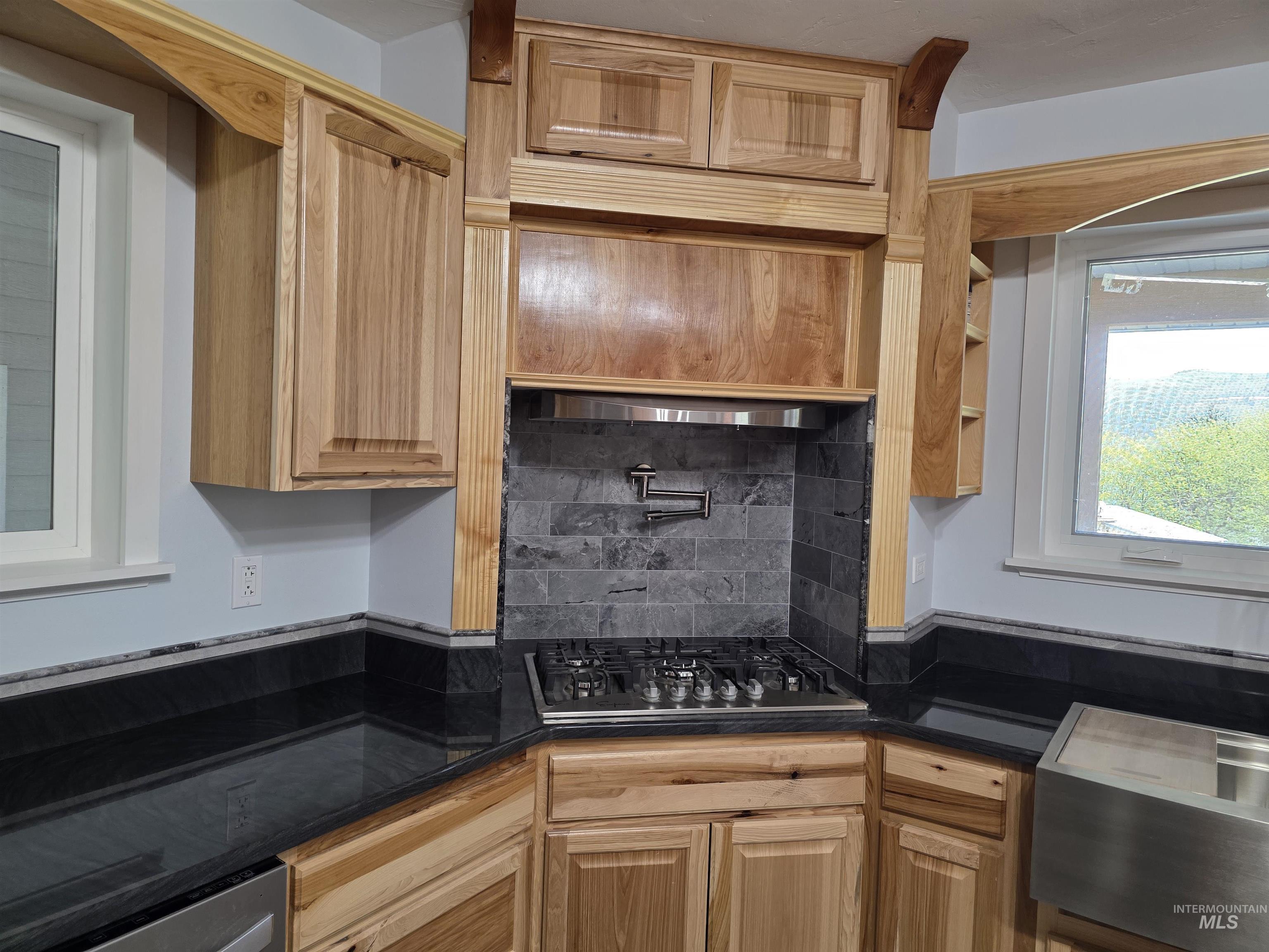 107 Pine Road Kamiah, ID 83536 - Photo 9 of 41 Corner gas range with stainless steel pot filler, set against a dark gray subway tile backsplash