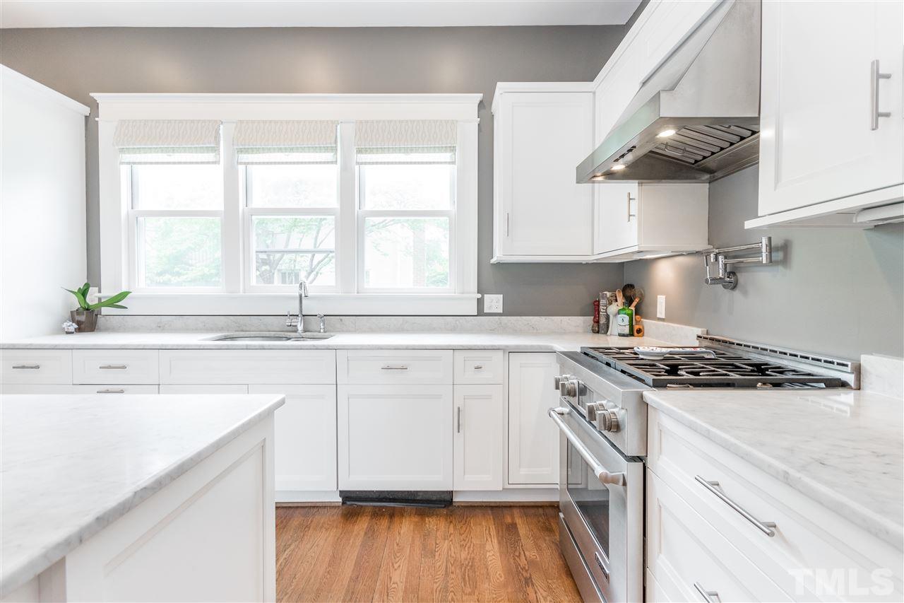 203 Forest Road Raleigh, NC 27605 - Photo 12 of 30 a kitchen with stainless steel appliances granite countertop a sink a stove and white cabinets with wooden floor