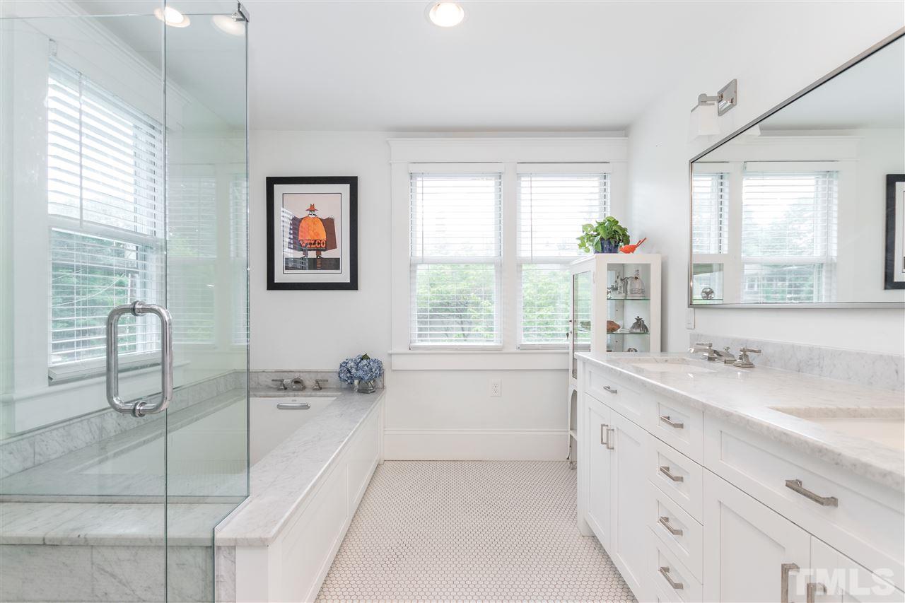 203 Forest Road Raleigh, NC 27605 - Photo 22 of 30 a spacious bathroom with a granite countertop sink a large mirror a bathtub and next to a window