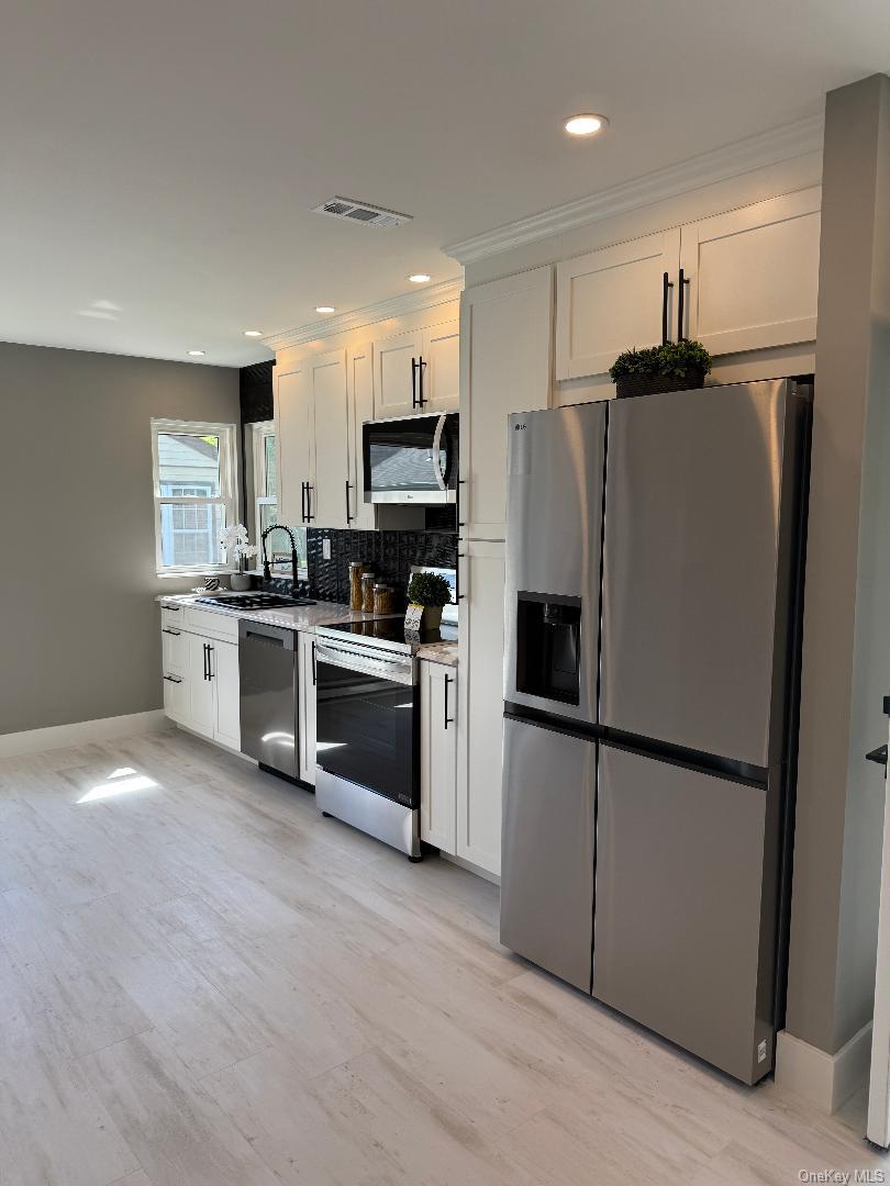 379 Larchmont Court Ridge, NY 11961 - Photo 5 of 17 a kitchen with stainless steel appliances a refrigerator sink and microwave