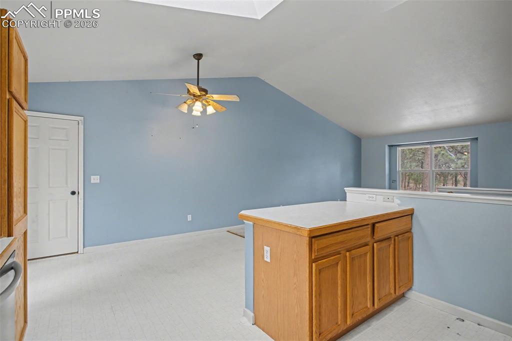 4944 Antelope Trail Elbert, CO 80106 - Photo 12 of 49 Kitchen featuring wood finish cabinets, lofted ceiling, light countertops, a ceiling fan, and a skylight