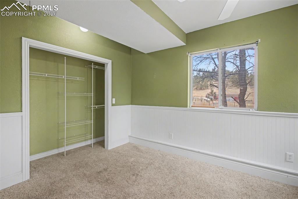 4944 Antelope Trail Elbert, CO 80106 - Photo 24 of 49 Unfurnished bedroom with wainscoting, carpet flooring, a closet, and ceiling fan
