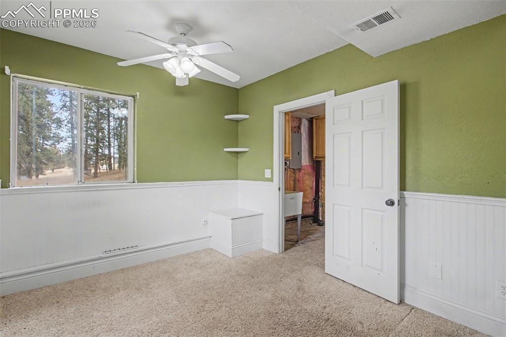 4944 Antelope Trail Elbert, CO 80106 - Photo 26 of 49 Unfurnished bedroom with wainscoting, carpet flooring, ceiling fan, and electric panel