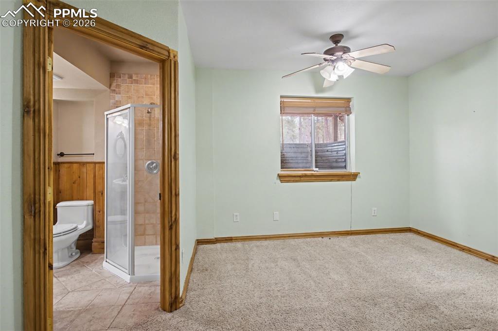 4944 Antelope Trail Elbert, CO 80106 - Photo 30 of 49 Unfurnished bedroom with ensuite bathroom, a ceiling fan, and light carpet