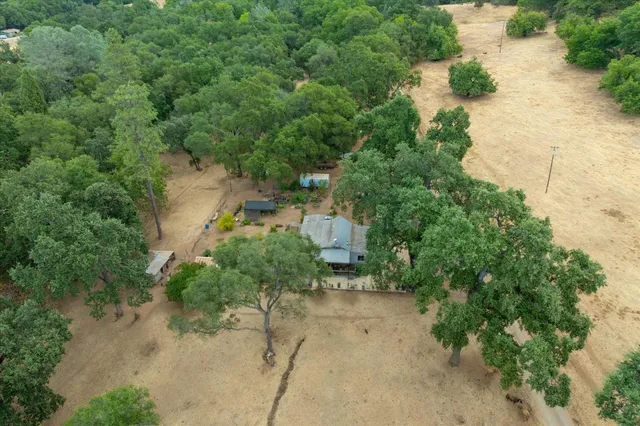 an aerial view of residential house with outdoor space and trees all around