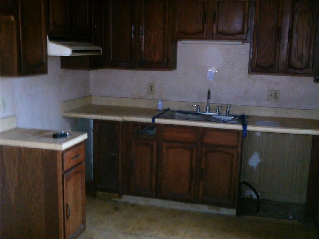 494 Gilmore Road New Castle, PA 16102 - Photo 3 of 7 a kitchen with stainless steel appliances a stove a sink a refrigerator and cabinets with wooden floor