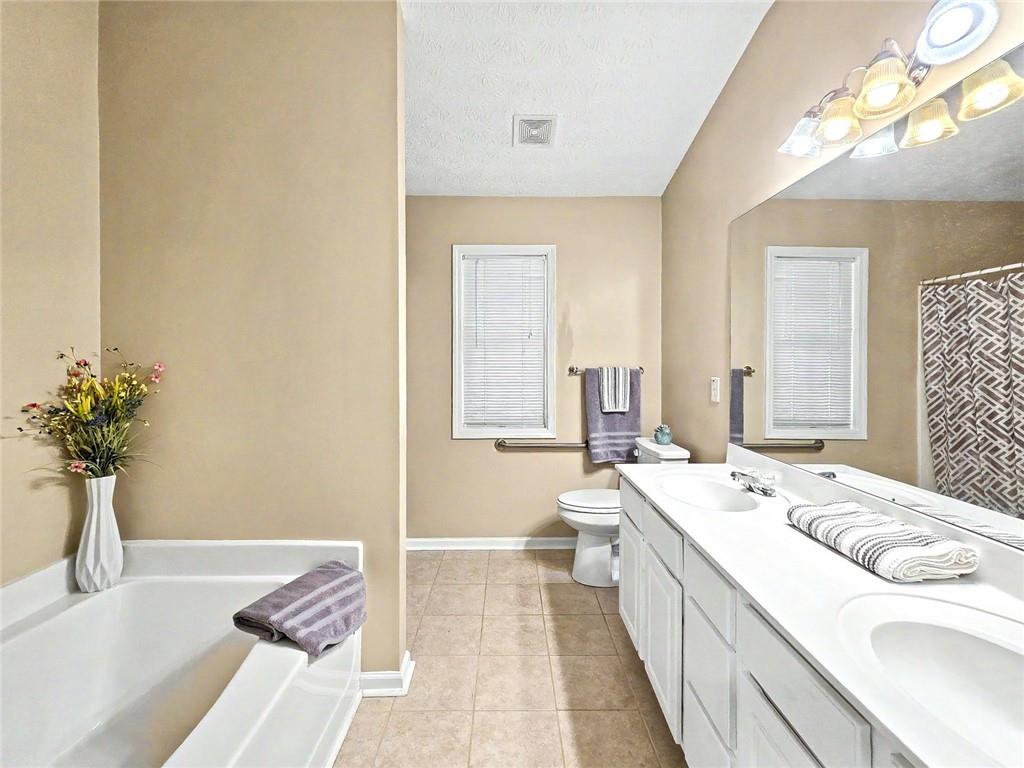 209 Diamond Valley Pass Canton, GA 30114 - Photo 18 of 27 a spacious bathroom with a double vanity sink a large mirror and a bathtub